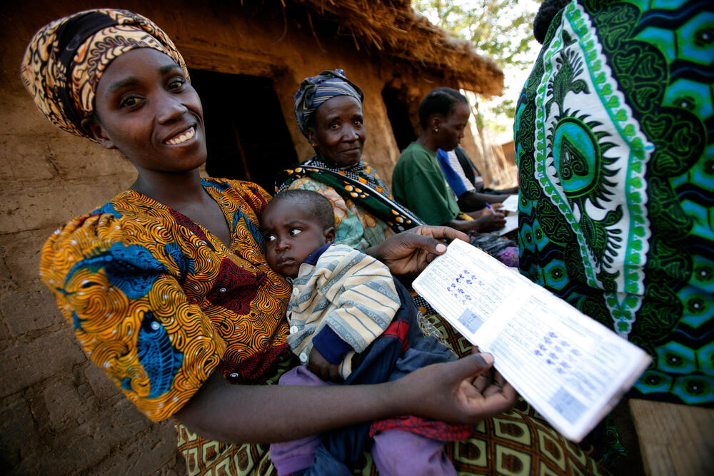 A woman holding a baby showing her savings book