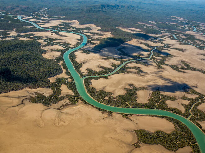Aerial view of the Fitzroy delta with a bright blue river running through sand