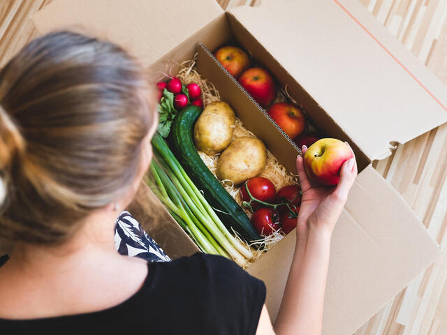 Woman looking into box of vegetables