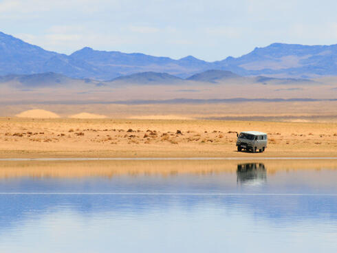 A camper van in the desert with mountains in the background