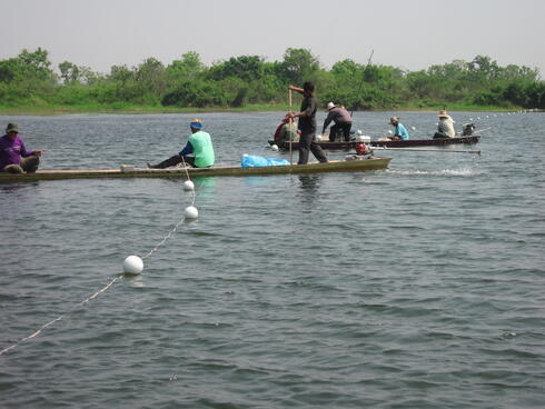 People in boats on a river laying out a rope