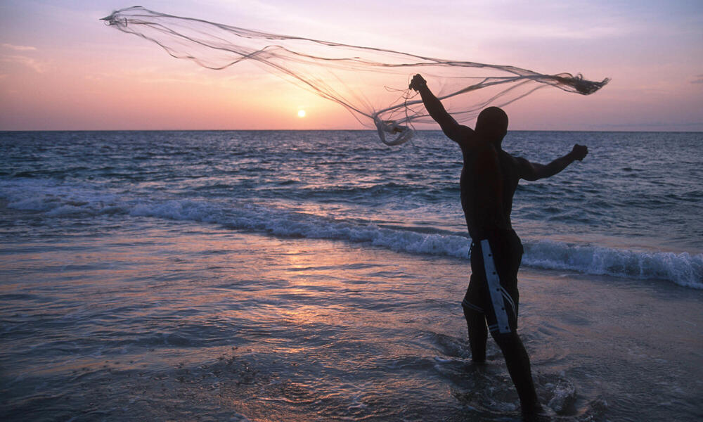 A fisherman casts his fishing net on the coast at sunset Gabon