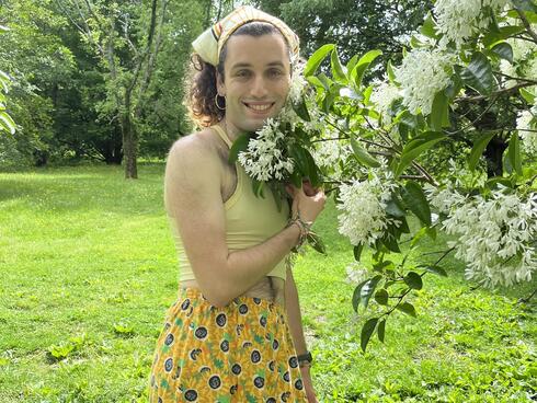 A person stands next to flowers.