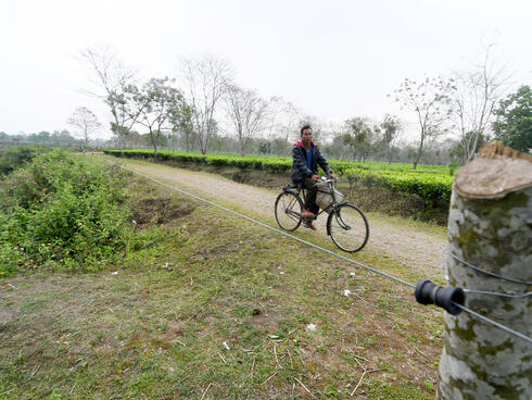 Man bikes along road beside fence