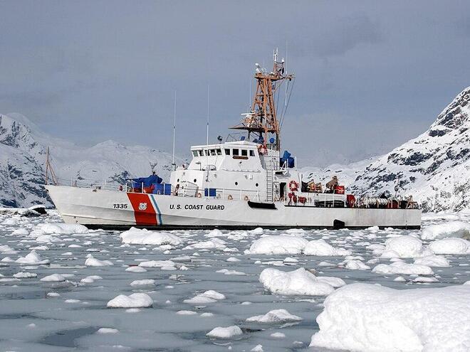 A coast guard ship in waters with glaciers around it.