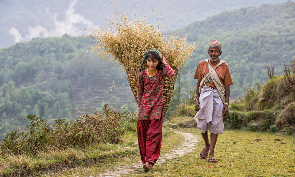 An older man and young woman walk along a path
