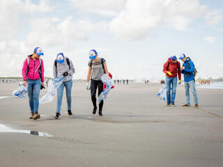 people picking up trash on a beach