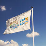 A white flag against a blue sky displays the logo for COP27