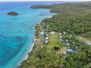 Aerial view of a fishing community along the coast nestled up against clear blue waters