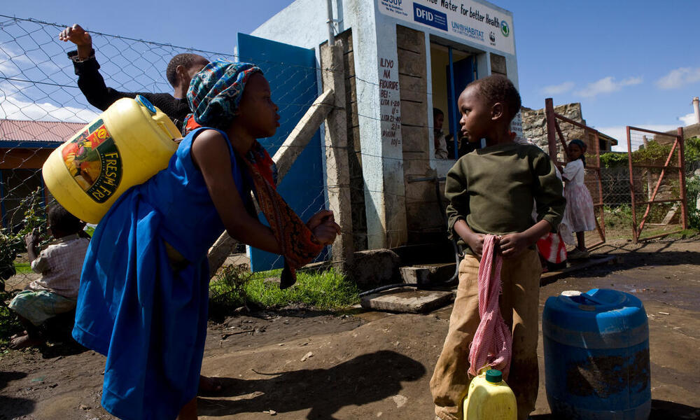 Children collect water at a kiosk in Kenya