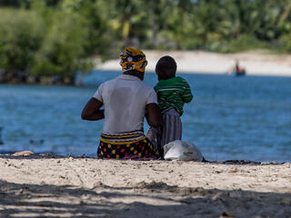 Mother and child sitting by waterside