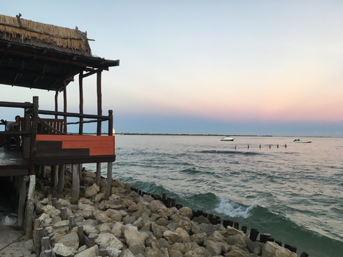 Rocks on shore of ocean and palapa next to shore