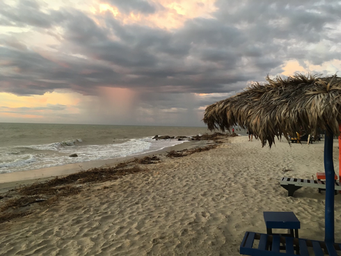 beach with palapa and storm rolling in over ocean